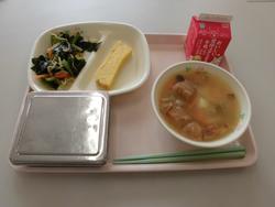 ピンクのトレイに、たけのこごはん、あつやきたまご、小松菜とわかめのおひたし、油麩の味噌汁、牛乳が並んだ給食の写真