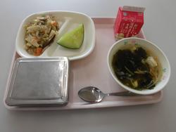 ピンクのトレイにご飯、中華丼の具、もやしとわかめのスープ、メロン、牛乳が並んだ給食の写真