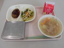 ピンクのトレイの上に、ごはん、ハンバーグトマトソースがけ、ブロッコリーとコーンのソテー、コンソメスープ、牛乳パックが並べられた給食の写真