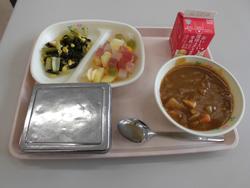 ピンクのトレイの上に、ごはん、南三陸かいせんカレー、わかめのささかまのソテー、りんごフルーツポンチ、牛乳パックが並べられた給食の写真