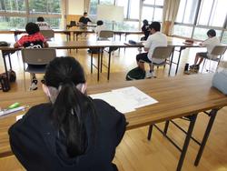 並べられた長机に間隔をあけて座り、机に向かって真剣に問題を解いている子どもたちの様子を後方から写した算数チャレンジ大会の写真