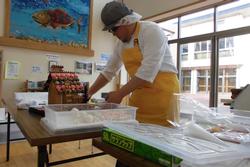 テーブルの上でクリームや材料を使いお菓子の家を組み立てているお菓子職人の写真