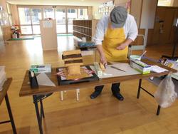 材料を並べた机でお菓子の家のパーツを作っている様子のお菓子職人の写真