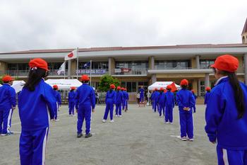 赤い帽子をかぶり青いジャージを着た生徒達が等間隔に並んでいる様子を後ろから撮影した写真