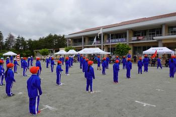 赤い帽子をかぶり青いジャージを着た生徒達が等間隔に並んでいる様子を右側から撮影した写真