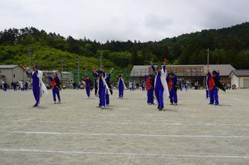 白や黒の衣装を着た子供達がよさこい踊りを披露し、両手を上に上げてポーズを決めている写真