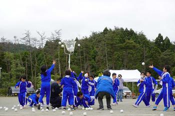 白組の子供達が白い球を白いカゴに向かって一生懸命投げている玉入れの様子の写真