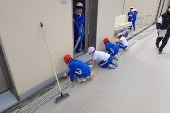 子ども達が座って雑巾で側溝を拭いたり、壁の汚れを落としたりしている様子の写真