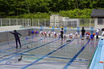 学校のプールの中に、たくさんの5･6年生が入ってプールの底を掃除をしている写真