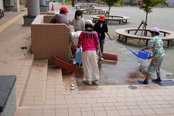 子ども達がジョウロを使いプランターの掃除をする様子の写真