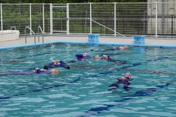 上下ジャージを着たままペットボトルを使い水面に浮く練習をしている着衣泳の写真