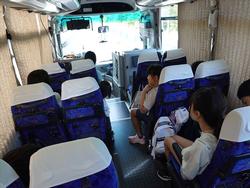 カーテンが閉まったバスの座席に子供たちが座り、それぞれ自由に過ごしている様子を写した車内の写真