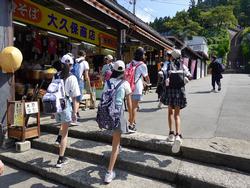リュックサックを背負っている子供たちが、階段を上った先にあるお土産屋さんの商品に目をやりながら歩いている修学旅行の様子の写真