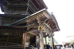 層をなす屋根と、精巧な彫刻が施された軒下部分が特徴の複雑な木造建築が印象的なさざえ堂を左斜めから撮影した写真