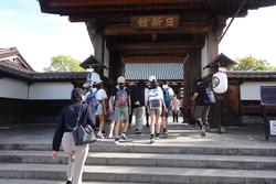 「日新館」と書かれた看板や、提灯が吊るされている門をくぐろうとしている、引率の先生や頭にキャップを被りリュックを背負った子供たちを捉えた写真