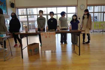 児童会の子供達がテーブルにチラシを貼り、募金箱を置いて募金活動をする様子の写真