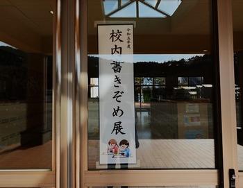 大きな窓ガラスに貼り付けられた「校内書きぞめ展」の案内ポスターの写真