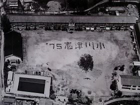 校庭に「’75 志津川小」と書かれた人文字がある空撮のモノクロ写真