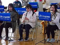 椅子に座ってクラリネットやサックスを演奏している3名の女の子をアップで写した写真