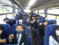 バスの車内で、座席に座った生徒たちが通路に顔を出したりこぶしを握ったポーズをして写した記念写真