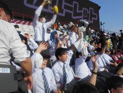 観客席で手をあげたり立ち上がったりして応援をする生徒たちの写真