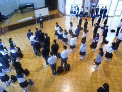 生徒たちが体育館に集まり、整列して先生の話を聞いている様子を上から撮影した写真