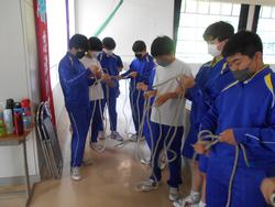 体育着姿の数人の男子生徒たちが、それぞれロープを手にして結び方の練習をしている様子の写真