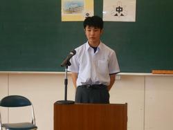 マイクが置かれた教壇に男子生徒が姿勢を正して立っている写真