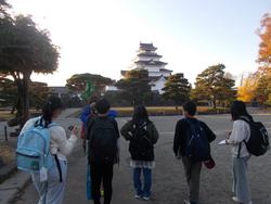 児童たちが白い天守閣のある鶴ヶ城に向かって歩いている写真