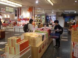 おみやげ店の売り場で児童たちが商品をかごに入れて買い物をしている写真