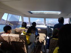 児童たちがライフジャケットを着て観光船の座席に座り、景色を楽しみながら航行している様子の写真