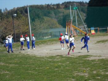 校庭で小学生たちが赤白帽をかぶって運動や遊びをしている様子の写真