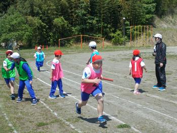 赤と白にわかれてトラックでリレーの練習をしている子供たちの写真