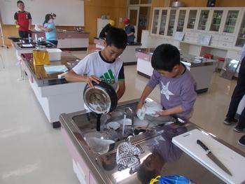 男の子2人で使った調理器具を洗っている調理実習の写真