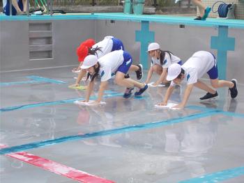 体操服姿の児童がプールの底を雑巾がけしている様子を写した写真