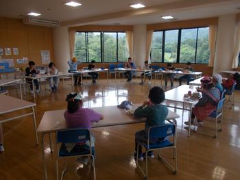 円型に並べた机に座り児童たちが給食を食べている教室内を写した写真