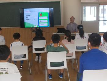 椅子に座った子供たちが前方のモニターを見ながら南三陸警察署の方の話を聞いている写真