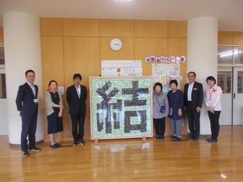 「結」という文字の大きなペナントを中心に置き、左に3名、右に4名の方が並んで写した記念写真