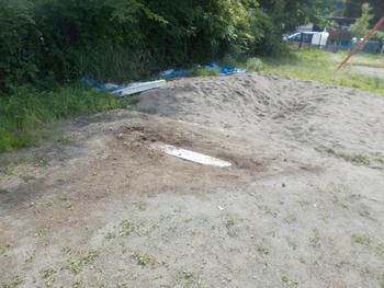 砂の中から白い踏み切り板が見えている写真