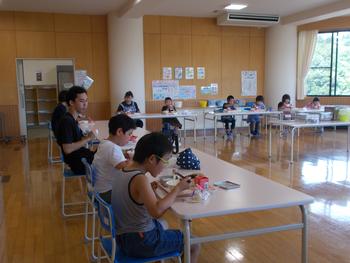 大きな長机をL字型に並べ、みんなで給食を食べている様子を写した写真