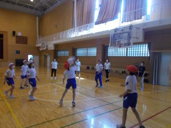 体操服姿の子供達のうち一人の女の子がビニールのボールを受け止めている様子を写した写真