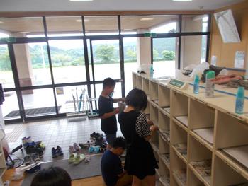 靴箱から靴を出し、ひとつずつ掃除をしている男女の児童達の写真