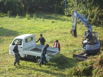 軽トラックの草を重機を使って運び出している写真