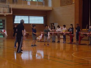 体育館の中で講師の先生方に指導されながら獅子や囃子の動きの練習をしている写真
