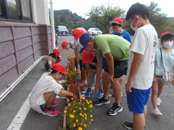 マリーゴールドとサルビアのプランターの周りを子供たちが囲んでいる写真