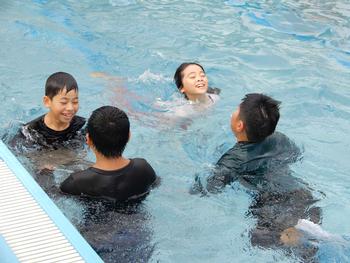 4名の子どもたちが洋服を着たままプールにはいっている写真