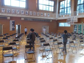 体育館の中にたくさんのパイプ椅子を並べている子供たちの写真