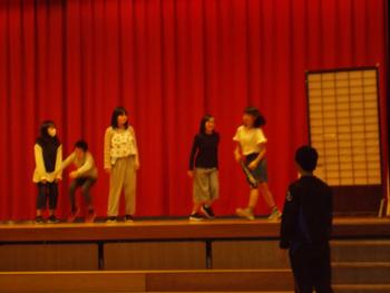舞台の上で5名の生徒が劇を行っている様子を写した写真