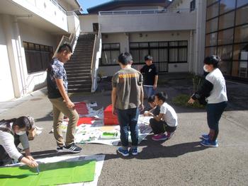 体育館の外で小道具を作成している生徒たちの写真