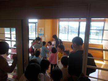 幼稚園の園児を玄関で見送っている小学生たちの写真